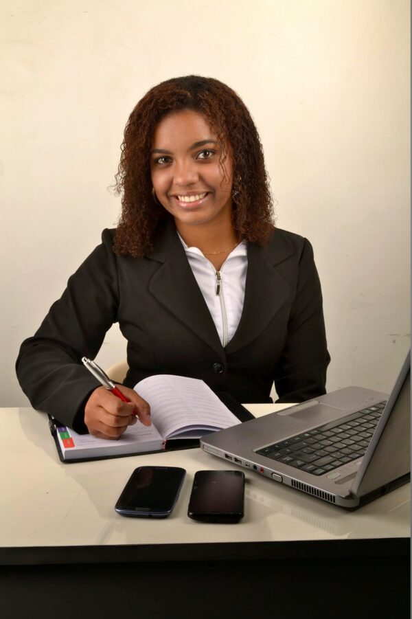 A smiling assistant at her desk with a planner and laptop
